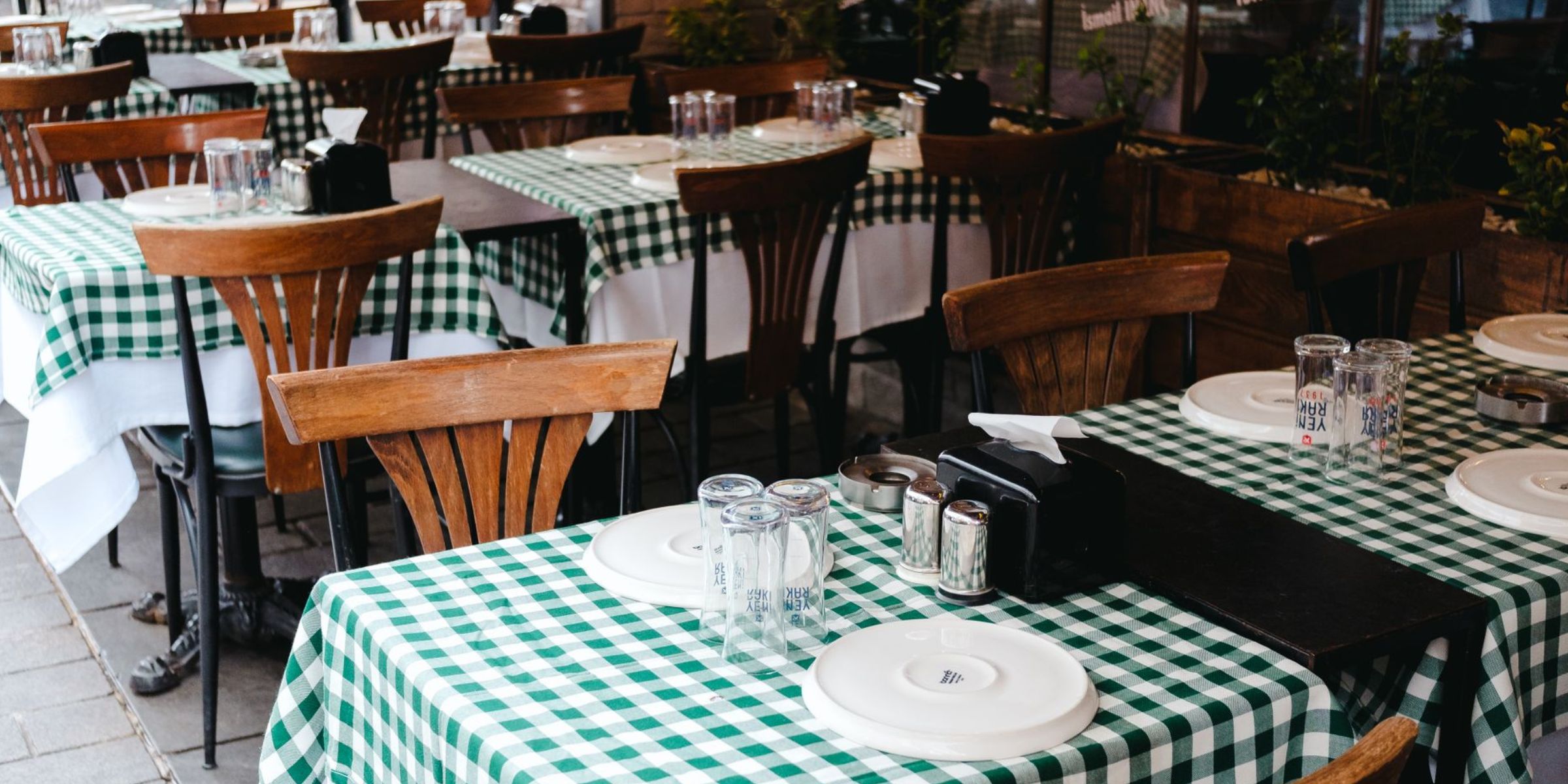 Salle à manger d'un restaurant avec nappes à carreaux, tables soigneusement dressées et chaises en bois accueillant les clients | Source : Pexels