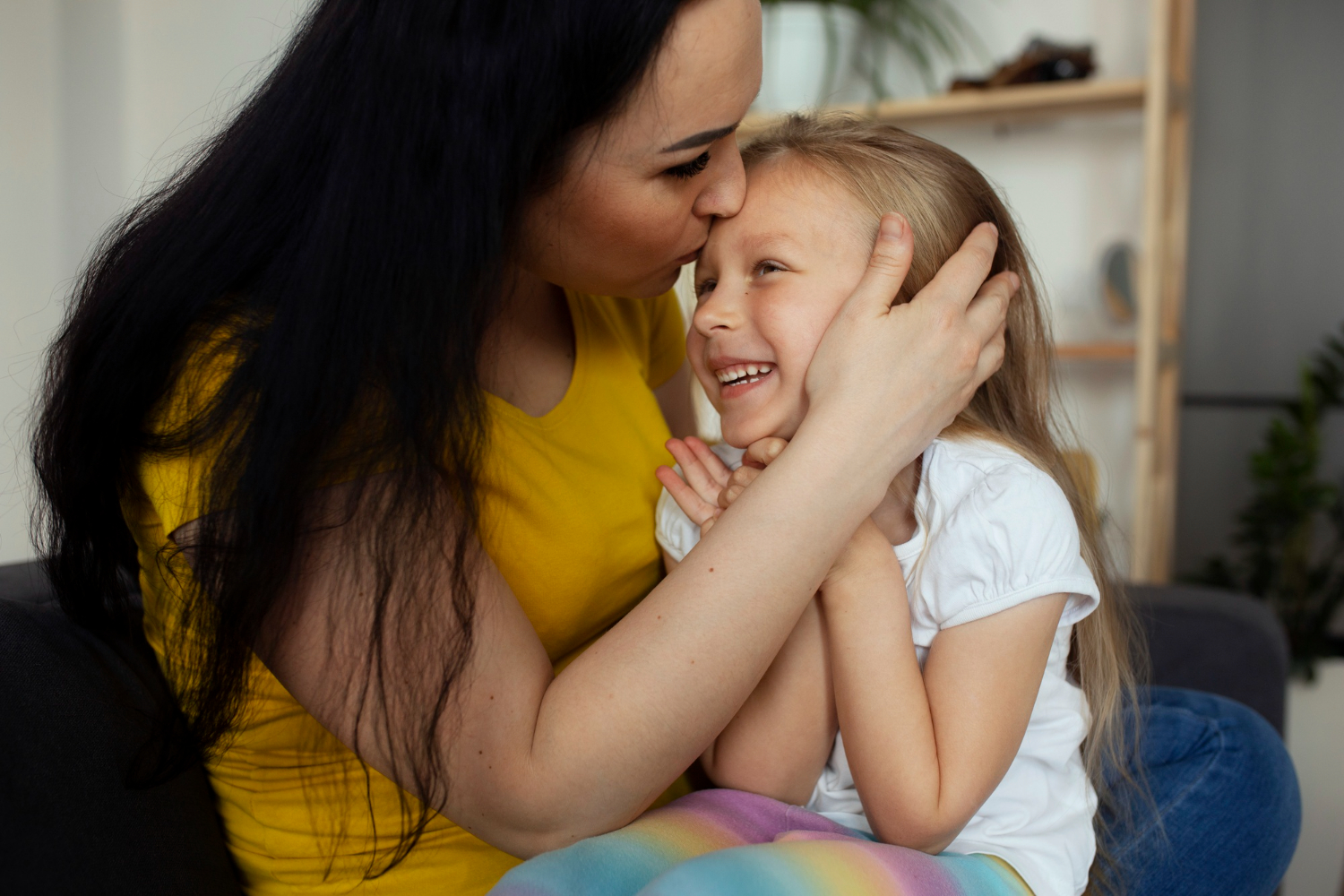 A woman kissing a little girl on the forehead | Source: Freepik