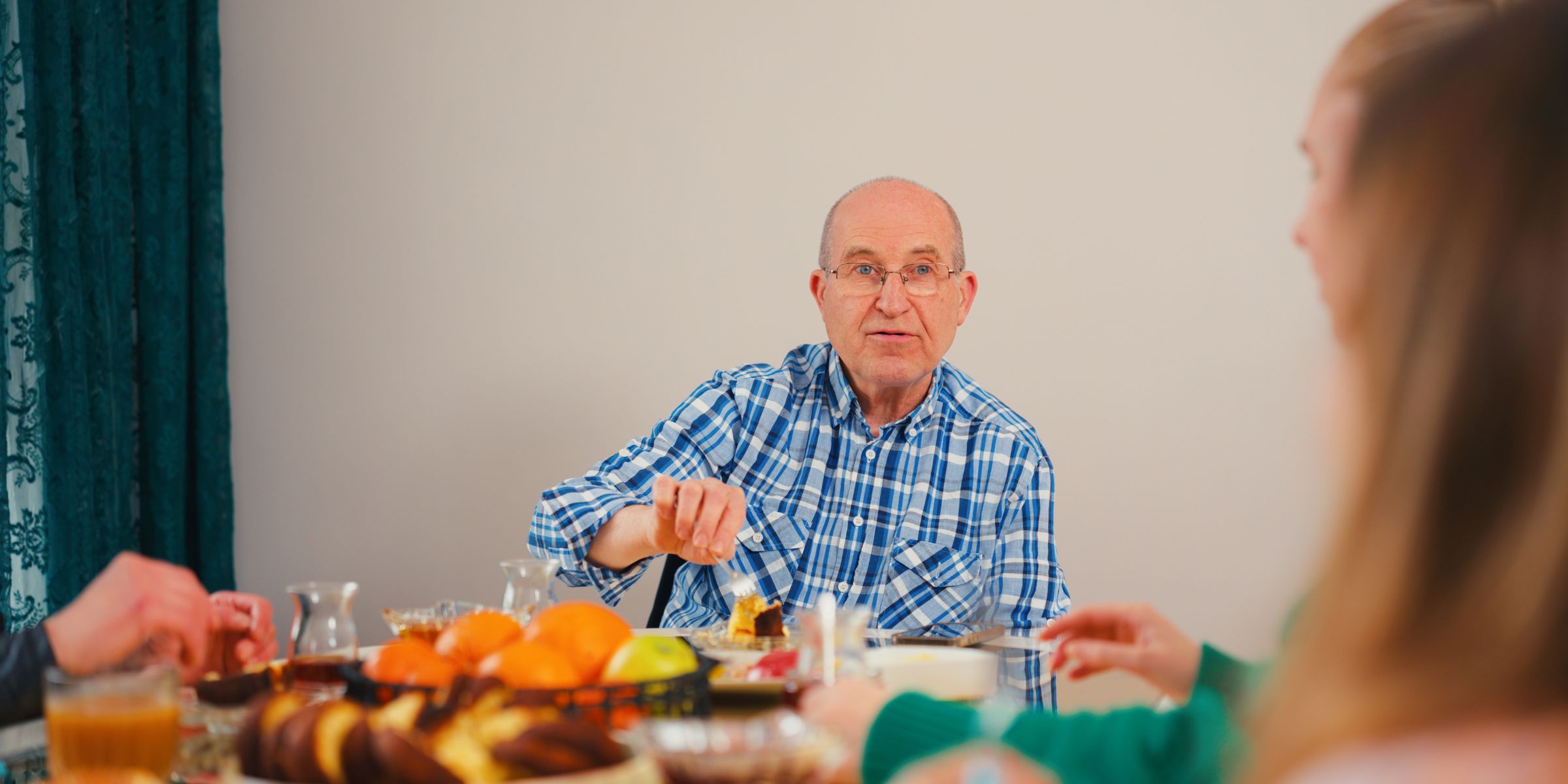 A grandfather is talking with his granddaughter during a family reunion meal | Source: Getty Images
