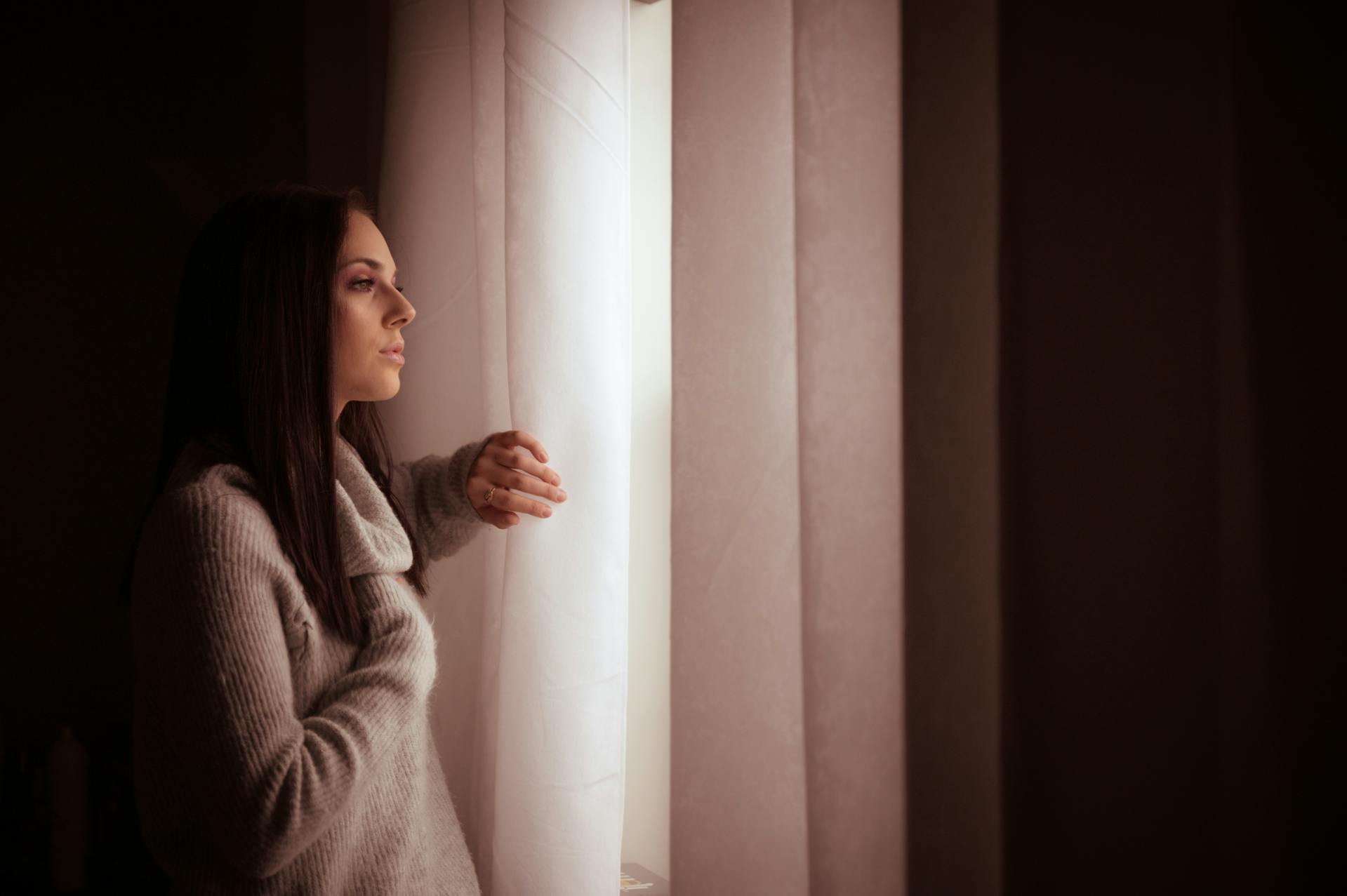 A woman staring thoughtfully out a window | Source: Pexels
