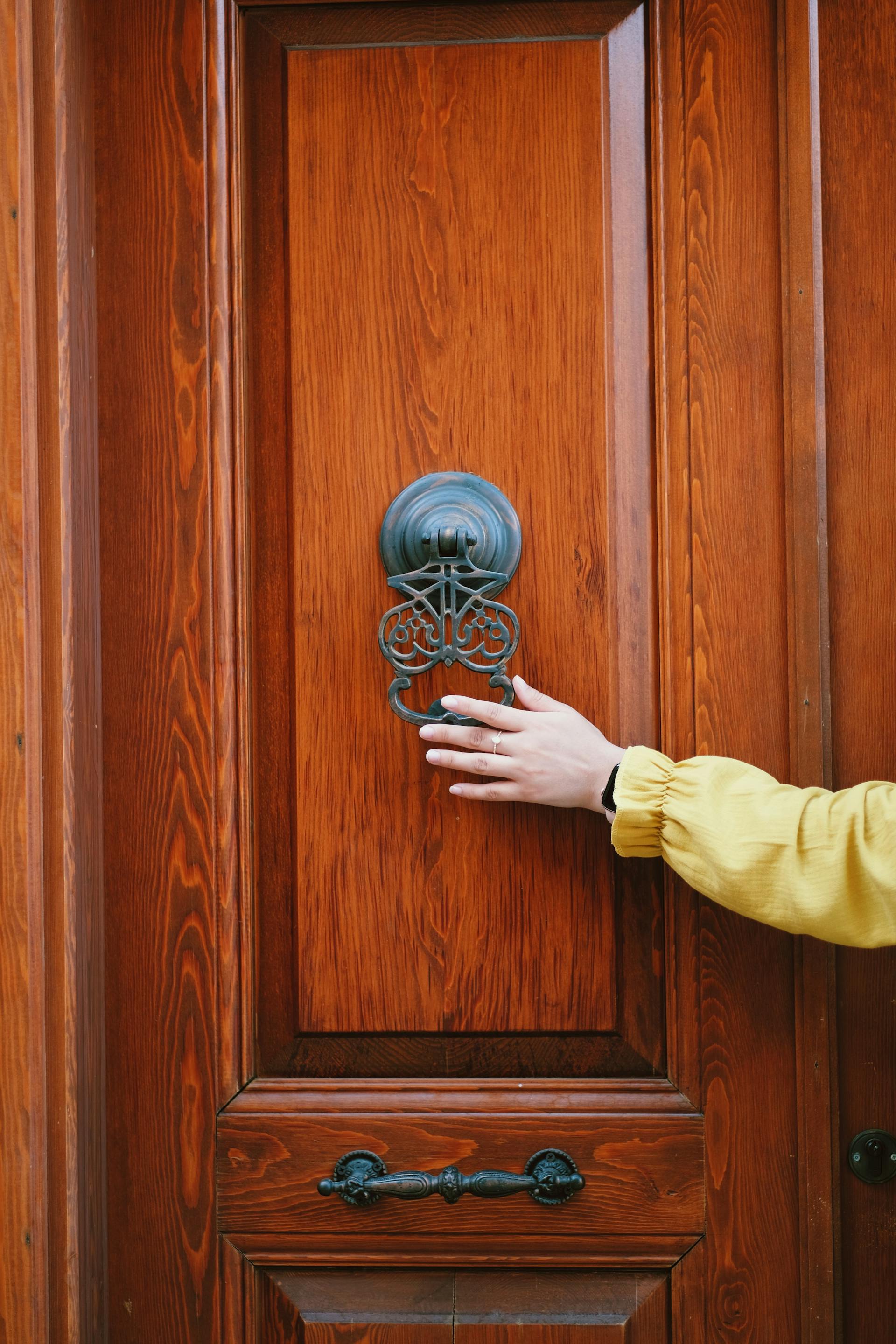 A distant shot of a person holding a door knocker | Source: Pexels