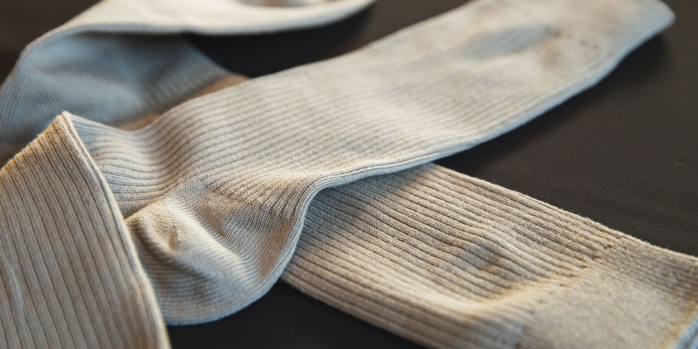 Close-up of a pair of light gray ribbed socks lying on a dark surface | Source: Pexels