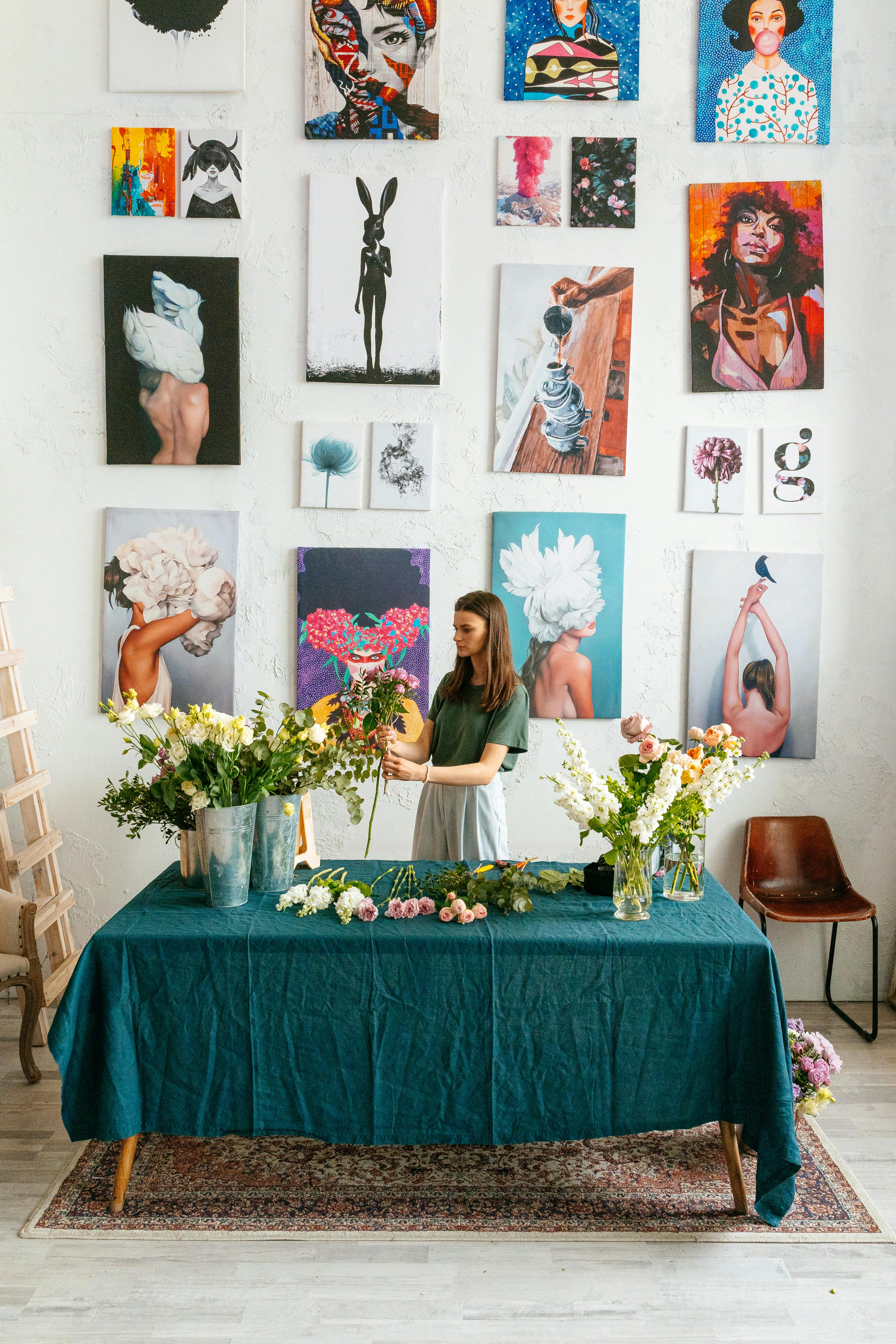 Woman holding flowers, standing next to a gallery wall | Source: Pexels