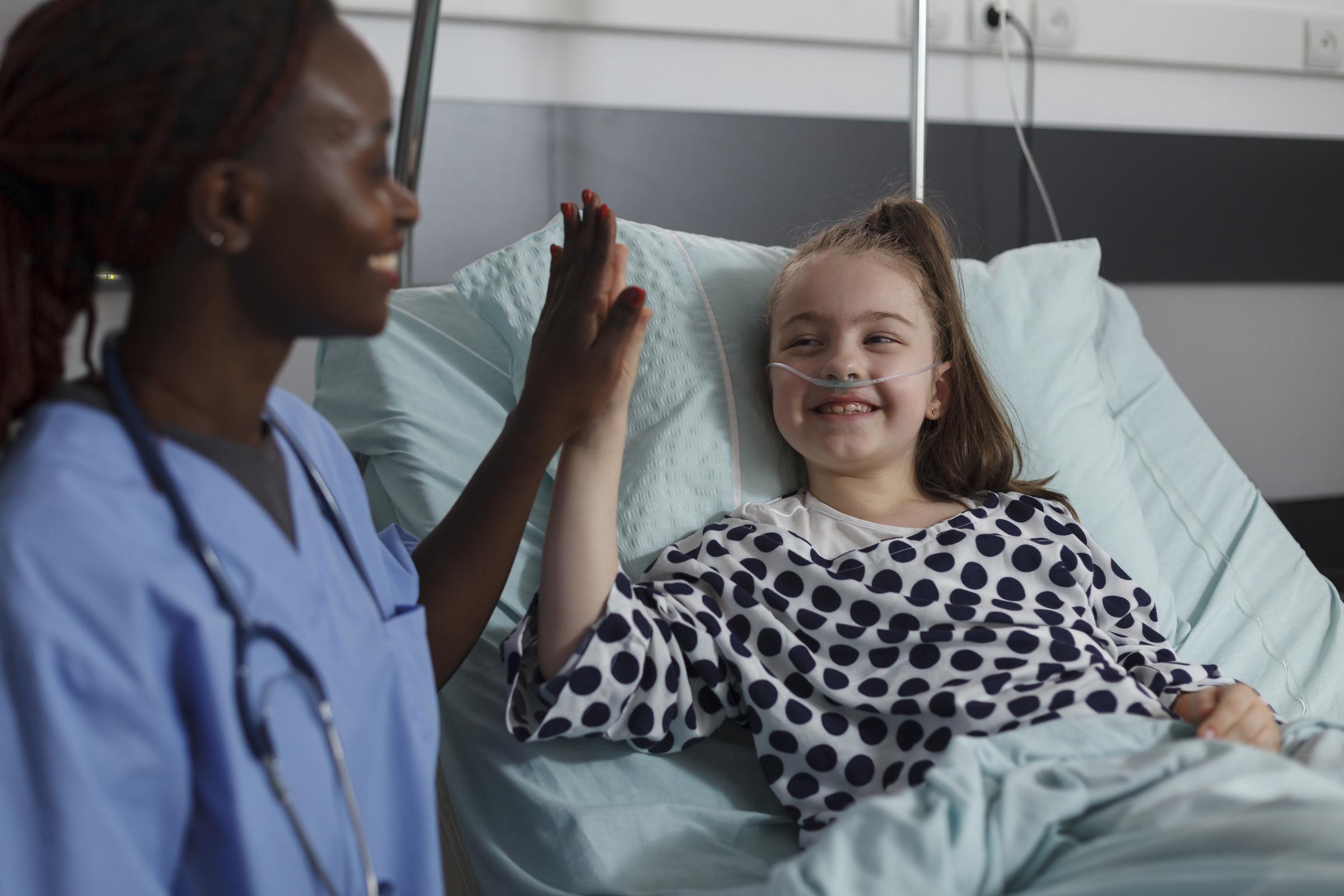 A nurse high-fiving a young patient | Source: Magnific
