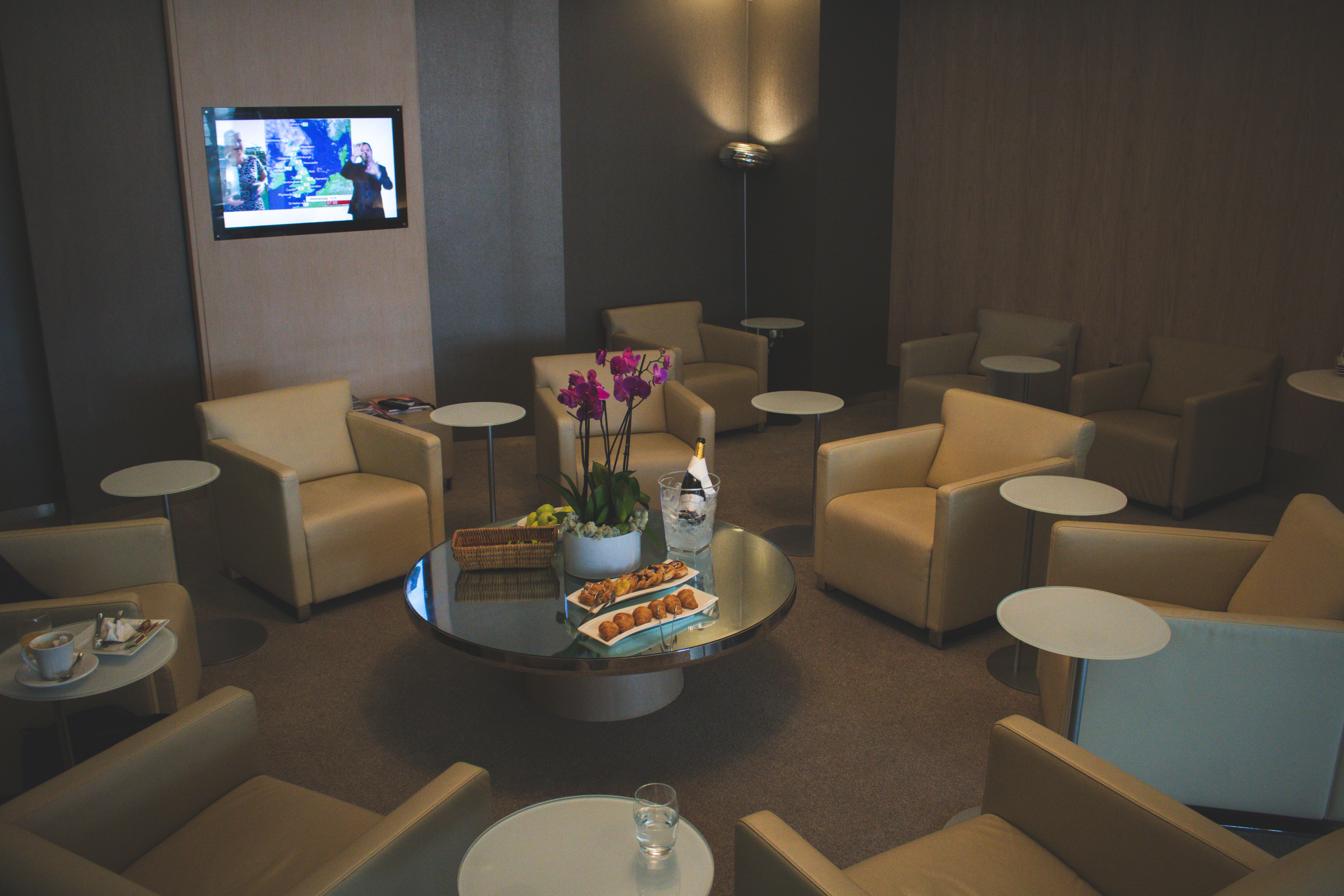 Elegant airport lounge with beige leather seats and orchid decor, offering comfort and luxury food service | Source: Pexels