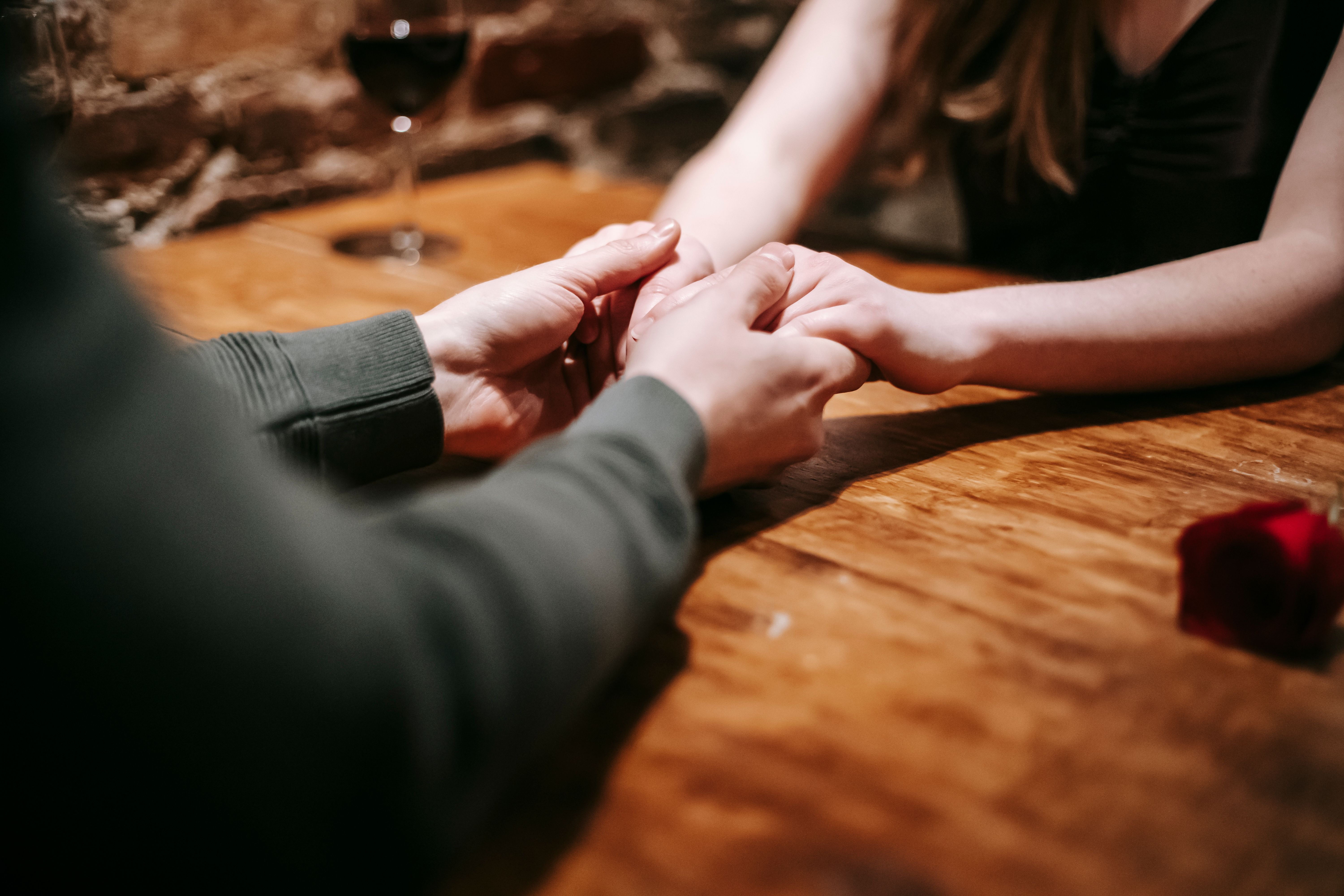 A couple enjoys a romantic moment, holding hands across a candlelit table in a cozy café | Source: Pexels