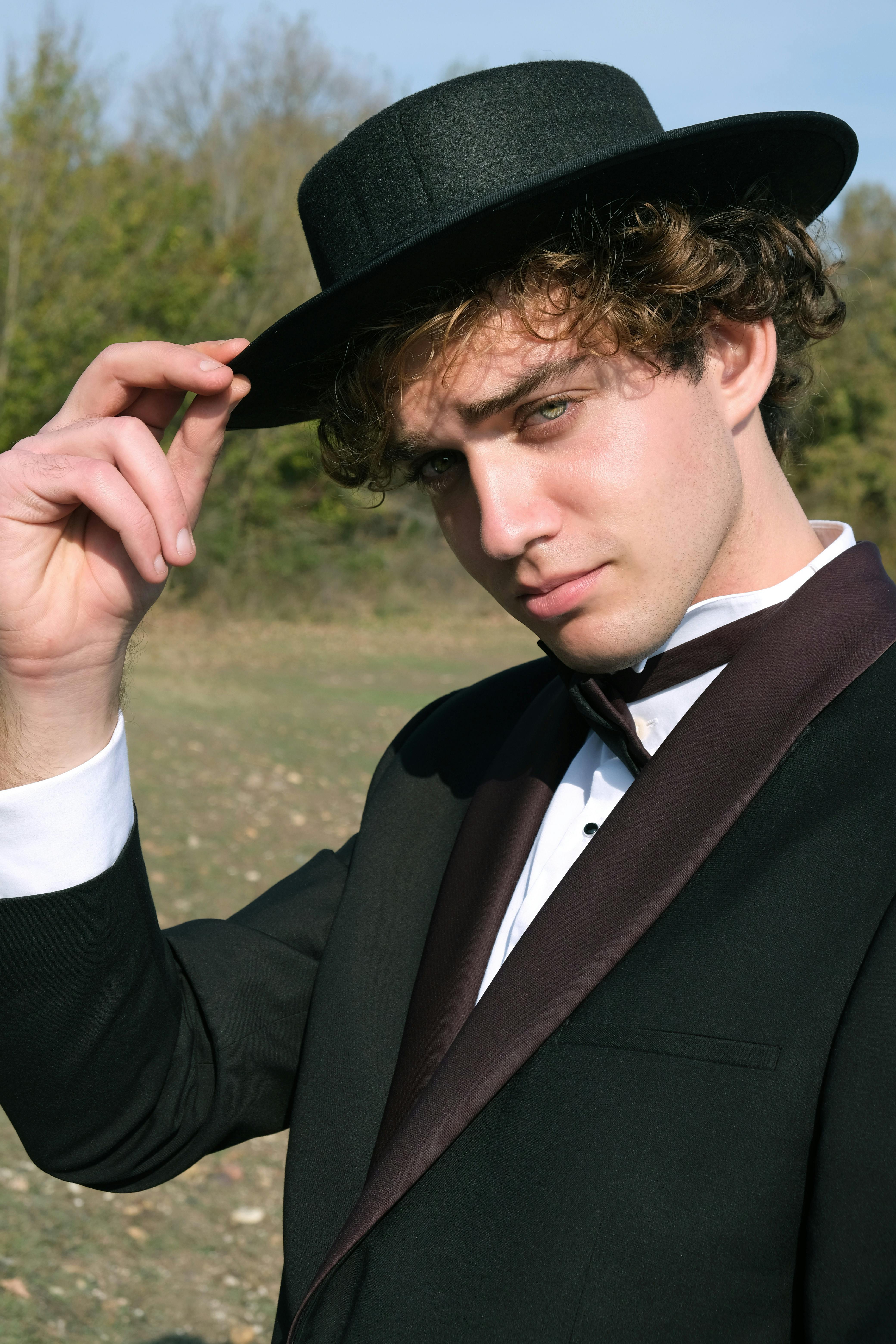 A teenage boy smiling while tilting his hat | Source: Pexels