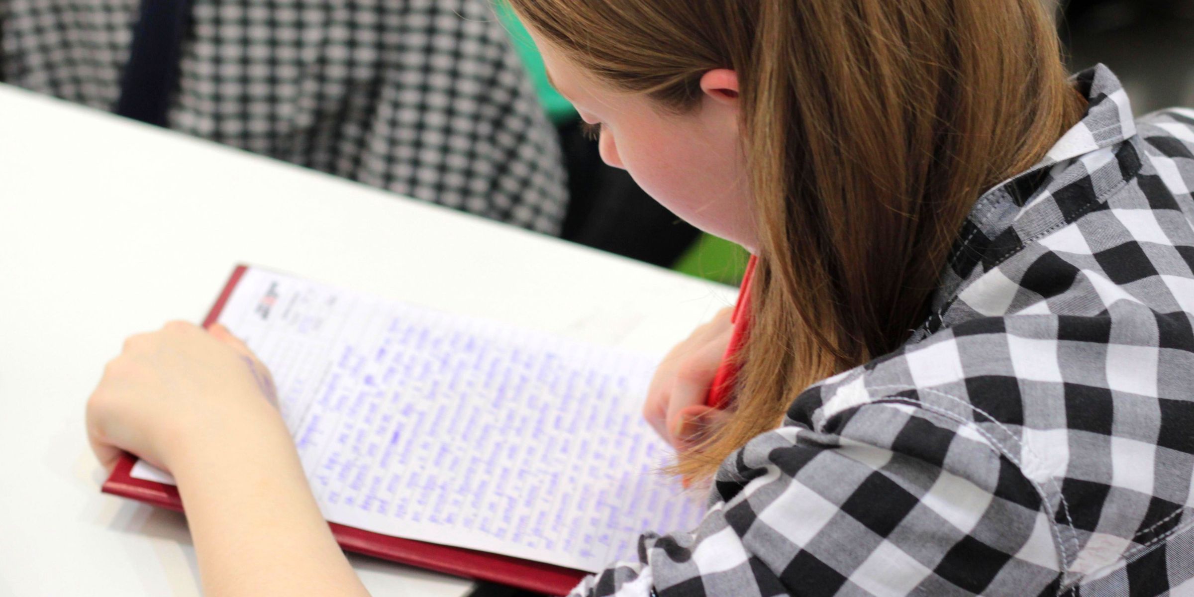 A close-up of a student writing in a notebook | Source: Pexels