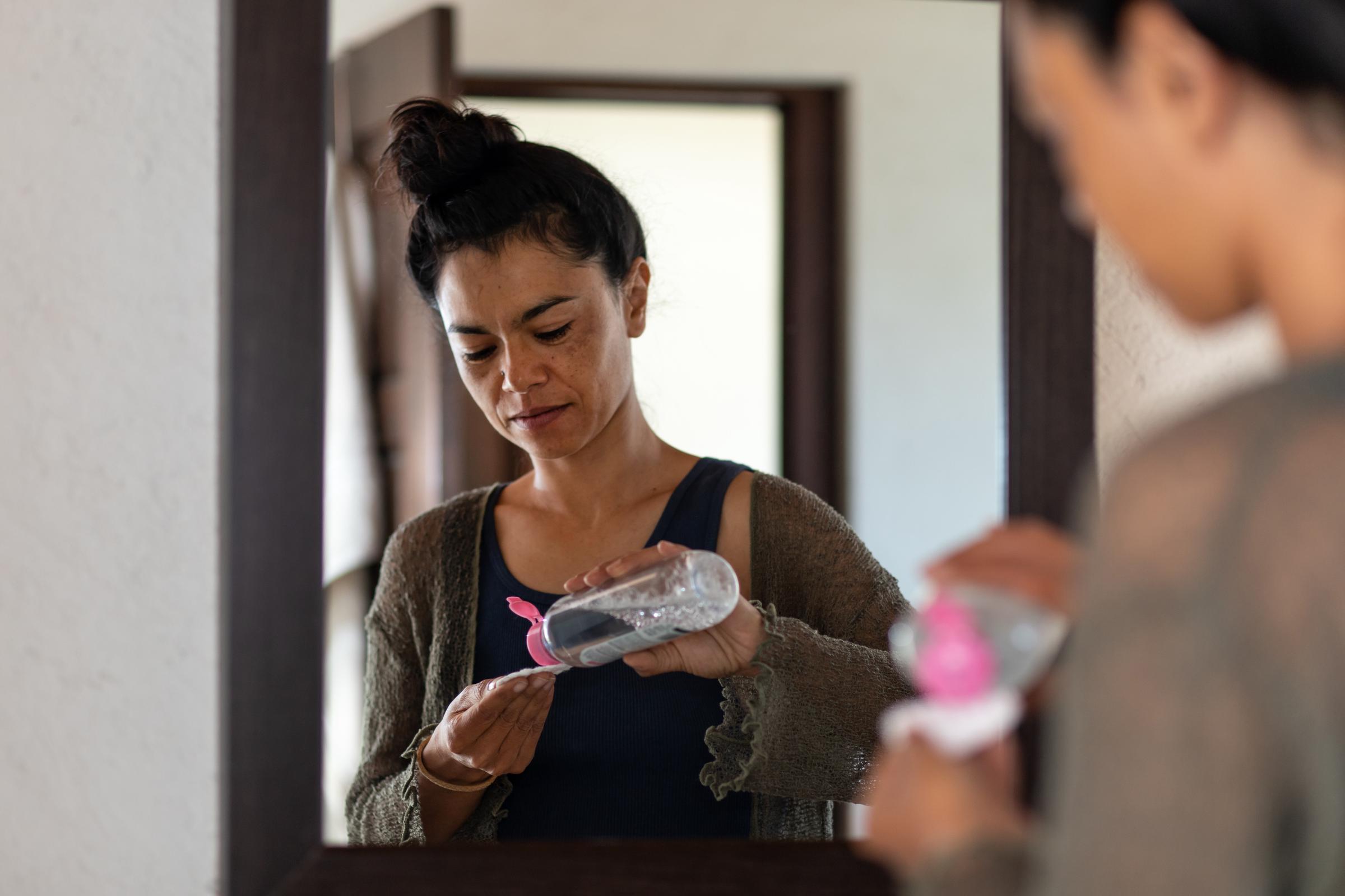 A woman applying micellar water to a cotton pad | Source: Getty Images