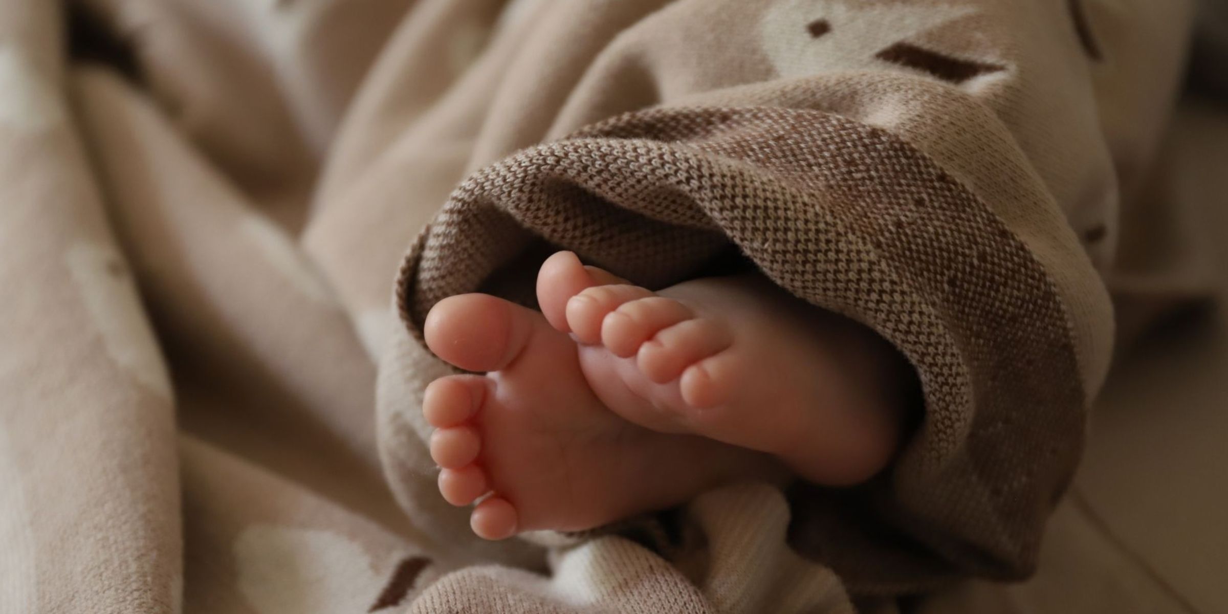 Adorable baby feet wrapped in a soft, cozy blanket | Source: Pexels